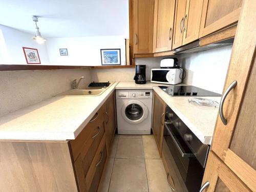une petite cuisine avec un lave-linge et un lave-linge dans l'établissement Appartement avec jardin proche plage et port, 2 chambres, parking privé, équipements complets - FR-1-481-56, à Combrit