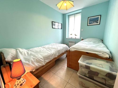 une chambre avec deux lits et une table avec une lampe dans l'établissement Appartement avec jardin proche plage et port, 2 chambres, parking privé, équipements complets - FR-1-481-56, à Combrit