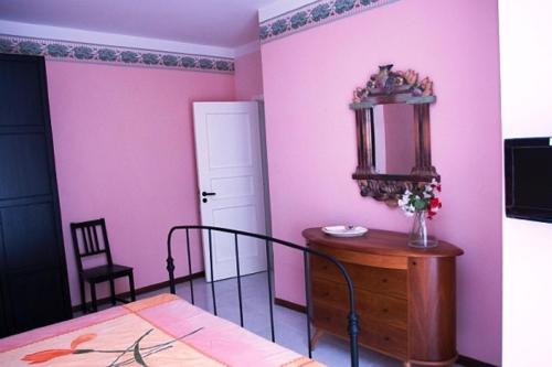 1 dormitorio con paredes rosas, mesa y cama en Camere In Centro, en Agropoli