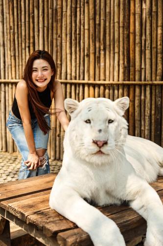 a woman is standing next to a white tiger at S.House168 in Chiang Mai