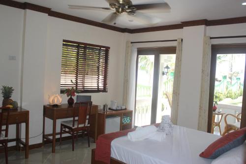 a bedroom with a bed and a desk and windows at The Beach House Carabao Island in San Jose
