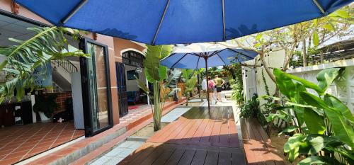 a blue umbrella on a wooden walkway with plants at An Bang Gold Coast Beach Villa in Hoi An