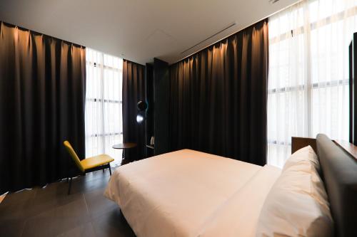 a bedroom with a bed and a chair and window at LE SEOUL HOTEL in Seoul