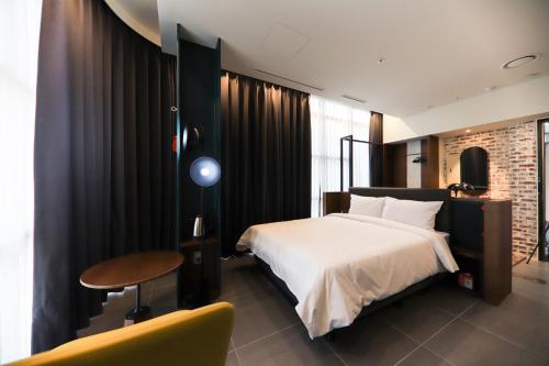 LE SEOUL HOTEL في سول: غرفة نوم بسرير وطاولة وكرسي