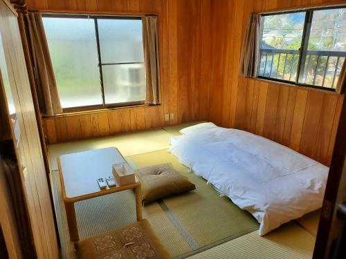 a bedroom with a bed and a table and two windows at Guest House Uminokyojyusya - Vacation STAY 84451v in Miyazaki