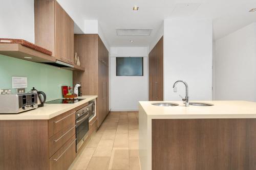 a kitchen with wooden cabinets and a sink at Belle Escapes 104 Swim-out Luxury Apartment in Palm Cove in Palm Cove