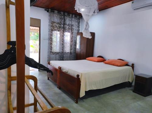 a bedroom with a bed with white sheets and orange pillows at Blue Corals Beach Bungalow in Madihe East