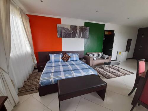 a bedroom with a bed and a couch at Jaria Apartments in East Legon