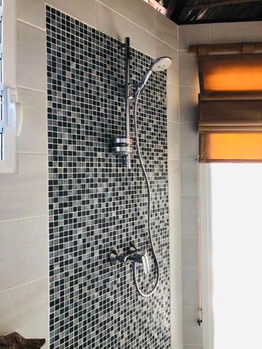a shower in a bathroom with a black tile wall at FILAO EDEN SAKALAVA in Antsiranana