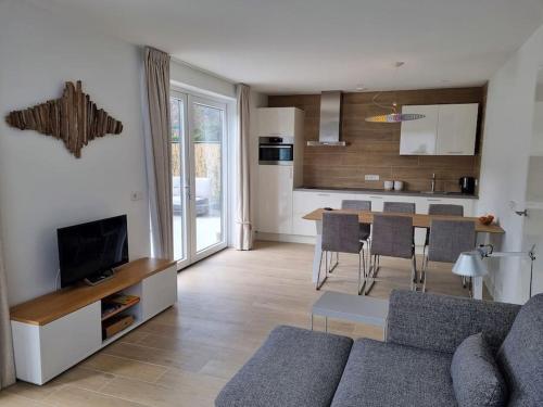 uma sala de estar com um sofá, uma mesa e uma cozinha em Vakantiewoning 1 aan zee, 400 meter van het strand em Zoutelande