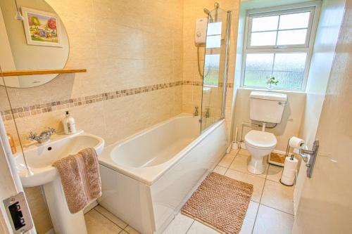 y baño con bañera, aseo y lavamanos. en Branch cottage en Limavady