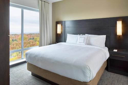 a large bed in a hotel room with a large window at Residence Inn by Marriott Albany Airport in Albany