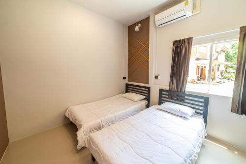 two beds in a room with a window at J Villa Betong - Private House in Betong