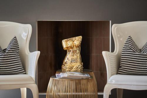 a gold vase sitting on a table next to two chairs at B&B Le Logge Luxury Rooms in Siena