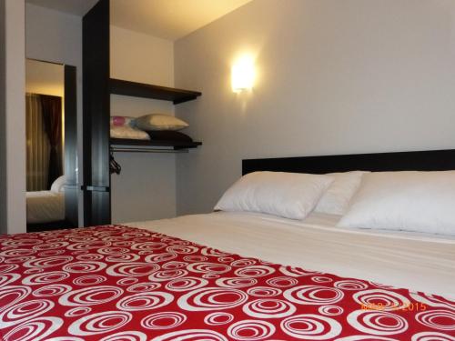 a bedroom with a bed with a red and white bedspread at Hotel San Marcos in Paipa