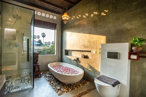 a bathroom with a tub and a glass shower at Le Chanthou Boutique in Siem Reap