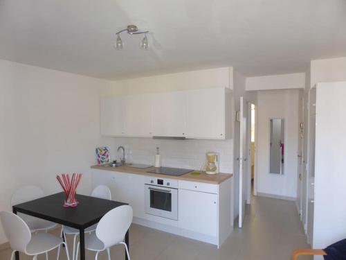 une cuisine avec une table noire et des appareils électroménagers blancs dans l'établissement Résidence La Rade Cassis, à Cassis