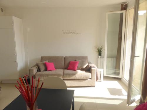 - un salon avec un canapé et 2 oreillers roses dans l'établissement Résidence La Rade Cassis, à Cassis