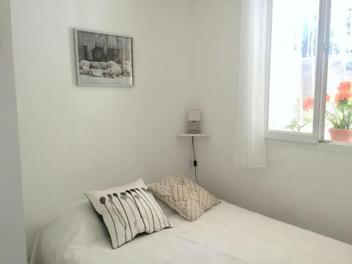 - un lit blanc avec deux oreillers dans une chambre blanche dans l'établissement Résidence La Rade Cassis, à Cassis