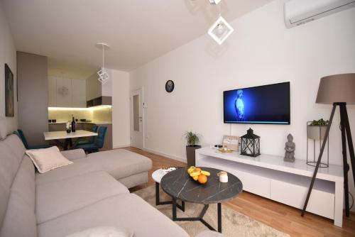 a living room with a couch and a tv on a wall at Apartman Allena Trebinje in Trebinje