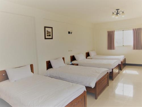 Zimmer mit 4 Betten und weißer Bettwäsche in der Unterkunft Dapu Inn in Juguang