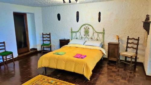 a bedroom with a bed with yellow sheets and two chairs at La Casa di Francesco in Perugia