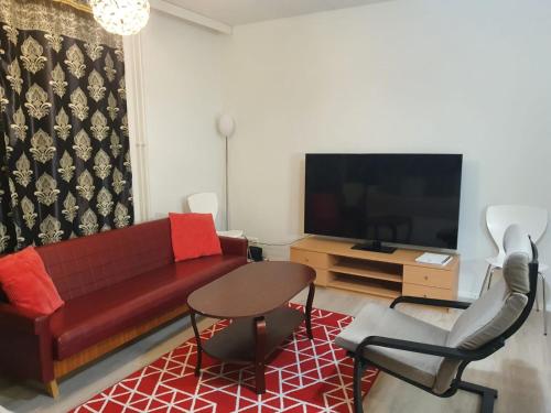 a living room with a red couch and a tv at Lovely Two Room Apartment in Helsinki in Espoo