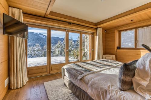a bedroom with a bed and a large window at Rock and Stars Megève in Megève