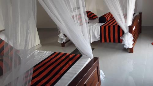 a bedroom with two beds with mosquito nets at Baagie Homestay in Ella