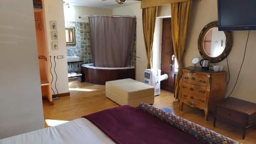 a bedroom with a bed and a bathroom with a tub at Hotel Rural Cayetana in Piedrahita