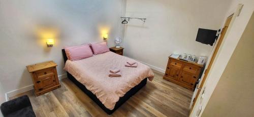a bedroom with a bed with pink sheets and two night stands at Deepcut Lodge Bed & Breakfast Self Service in Camberley