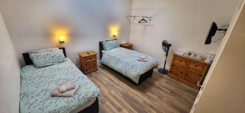 Habitación pequeña con 2 camas y suelo de madera. en Deepcut Lodge Bed & Breakfast, en Camberley