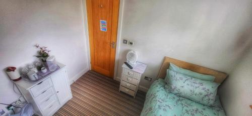 a small bedroom with a bed and a night stand at Deepcut Lodge Bed & Breakfast Self Service in Camberley