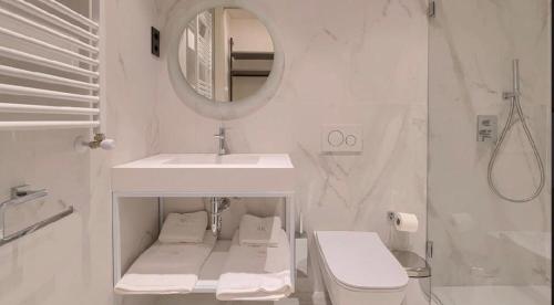 Abando Suites by Next Stop Bilbao في بلباو: حمام أبيض مع حوض ومرآة