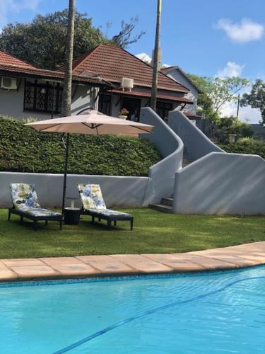 a pool with a slide and two chairs and an umbrella at The Midlands Hotel in Pietermaritzburg