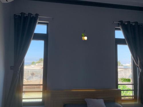 a bedroom with two windows with a view of the ocean at Nomad Stay in Phan Rang