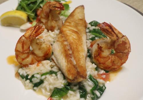 a plate of food with shrimp and rice and greens at Hotel Krone in Mondsee