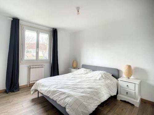 a white bedroom with a bed and a window at La VILLA Ismaila in Sainte-Feyre