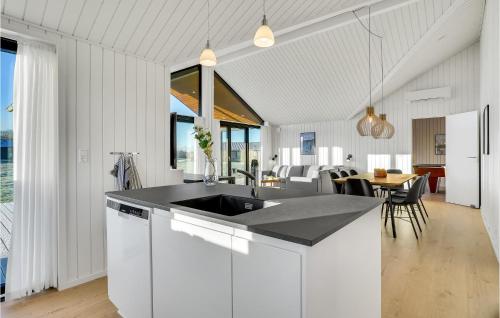 eine weiße Küche mit einem Waschbecken und einem Tisch in der Unterkunft Amazing Home In Hrve With Sauna in Hørve