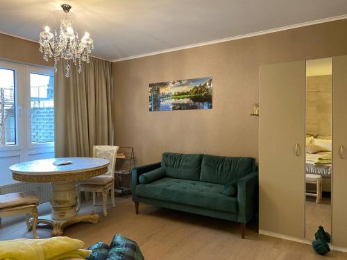 Una sala de estar con un sofá verde y una mesa. en Studio Montaigne, en Lieja