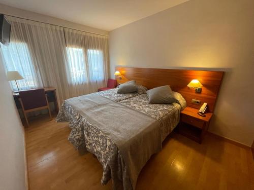 une chambre d'hôtel avec un lit et une table avec un téléphone dans l'établissement Hotel Arturo, à La Pobleta de Bellvei