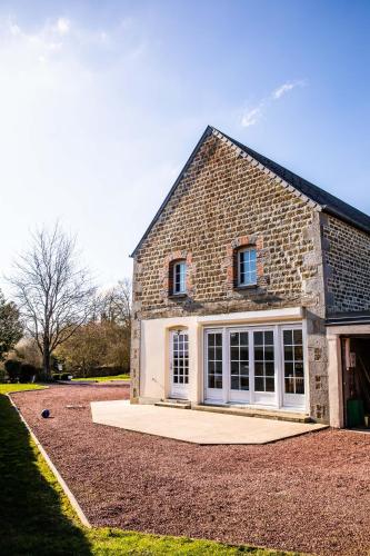 une maison en briques avec des portes blanches et une allée. dans l'établissement La Minoterie, à Tessy-sur-Vire