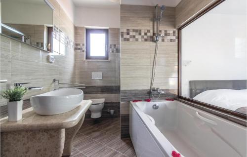 a bathroom with a white tub and a bed at Awesome Home In Bibici With Jacuzzi, Sauna And Wifi in Bibići