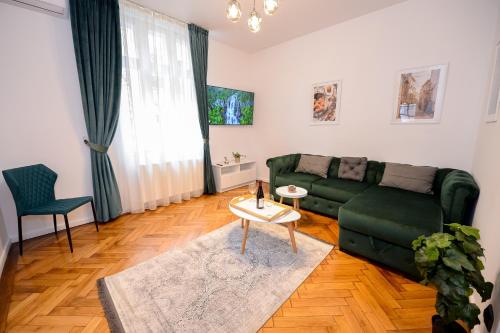 a living room with a green couch and a table at Villa Maria De Luxe in Bucharest