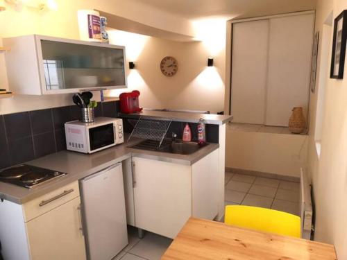 a small kitchen with white cabinets and a microwave at T2 - Coeur d'Ecusson in Montpellier