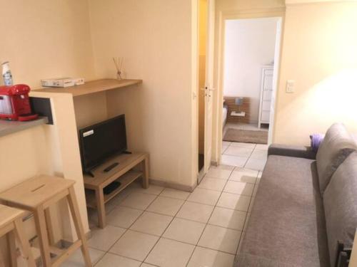 uma sala de estar com uma televisão e um sofá em T2 - Coeur d'Ecusson em Montpellier