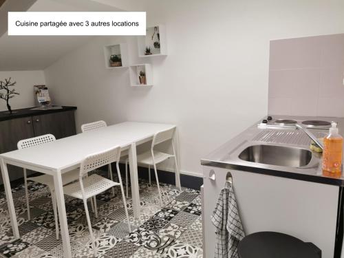 cocina con fregadero, mesa blanca y sillas en Logement - Nuit tendance centre ville de Mâcon E, en Mâcon