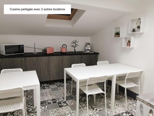 kuchnia z 2 białymi stołami i białymi krzesłami w obiekcie Logement - Nuit tendance centre ville de Mâcon E w mieście Mâcon