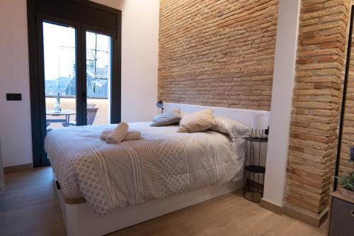 a bedroom with a bed and a brick wall at Niu del Sol in Vic