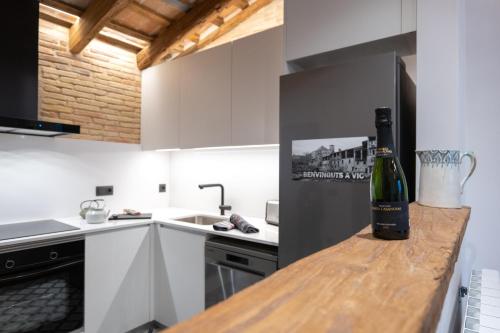 una cocina con una botella de vino en una barra de madera en Niu del Sol en Vic
